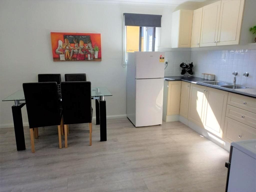 Une cuisine moderne avec un coin repas, comprenant un réfrigérateur, des placards et une table avec des chaises.