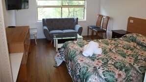 A hotel room with a bed, a sofa, a TV, a window, and a desk. - Coburg Motor Inn (Coburg North)