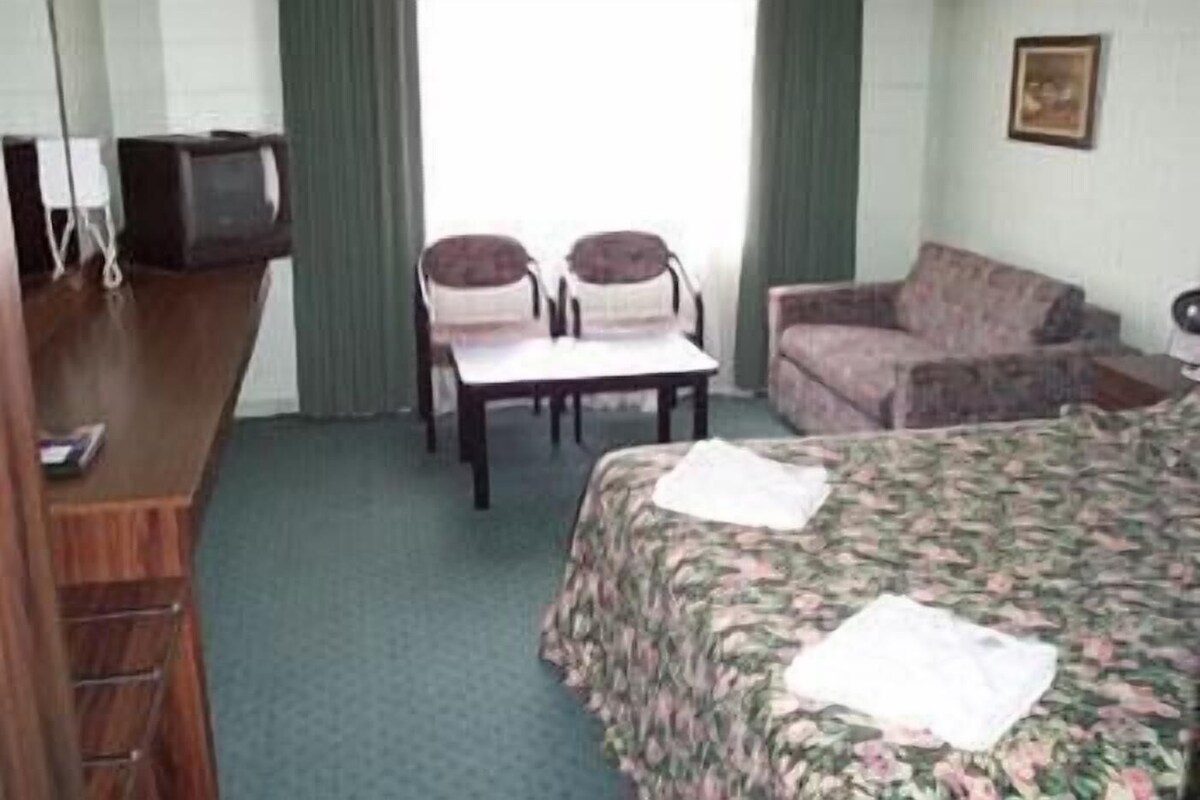 Een hotelkamer met een bed, een bureau, een stoel en een televisie.