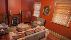 A living room with a fireplace, two armchairs, a sofa, and a small table. - Steampacket Inn (Echuca)