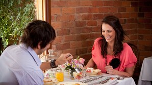 A dining table with a meal, a newspaper, and a flower arrangement. - Steampacket Inn (Echuca)