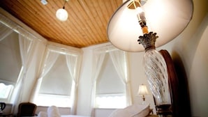 A hotel room with a wooden ceiling, a bed with white linens, and a table lamp with a decorative base. - Steampacket Inn (Echuca)