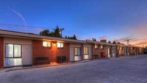 Filas de edificios tipo motel, con habitaciones individuales, cada una con puerta, ventanas y un pequeño espacio al aire libre para sentarse.