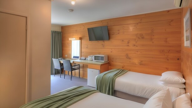 Habitación de hotel con dos camas, un escritorio con microondas, televisión y refrigerador pequeño.
