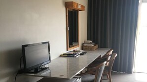 Habitación de hotel con televisión de pantalla plana, refrigerador pequeño, escritorio de madera y espejo.
