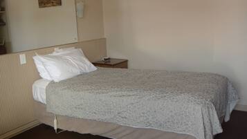 A hotel room with a single bed, a nightstand, and a wall-mounted telephone.