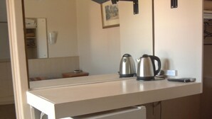 A compact kitchenette with a white countertop, a small refrigerator, and a kettle. - Travellers Rest Motel (Bairnsdale)