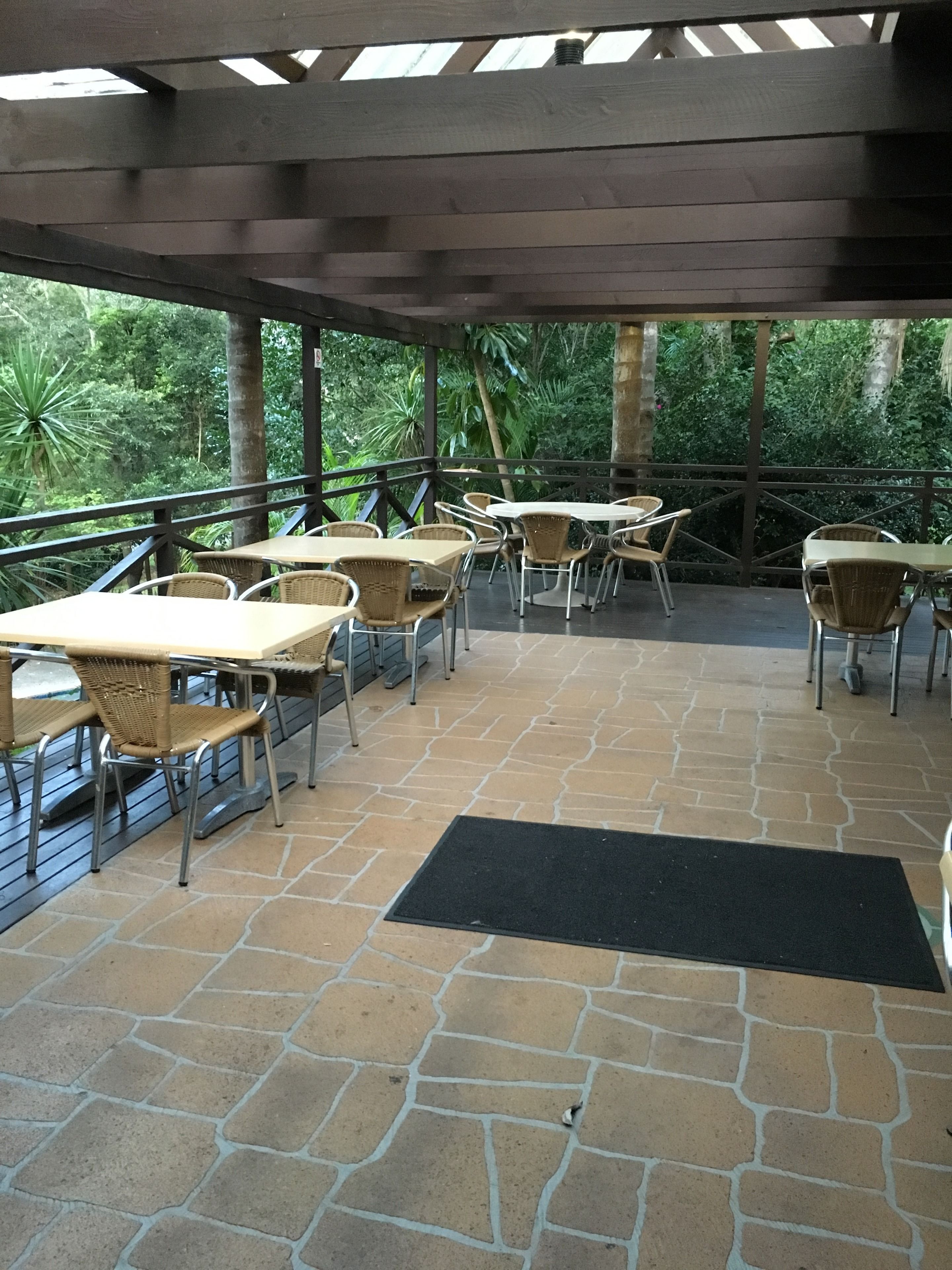 An outdoor patio with stone flooring, wicker tables, and chairs.