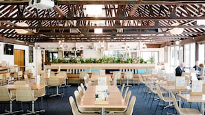 A spacious restaurant with high ceilings, wooden beams, and a central bar area. Tables are arranged around the bar, and there are several chairs and dining tables. - Avoca Beach Hotel (Avoca Beach)