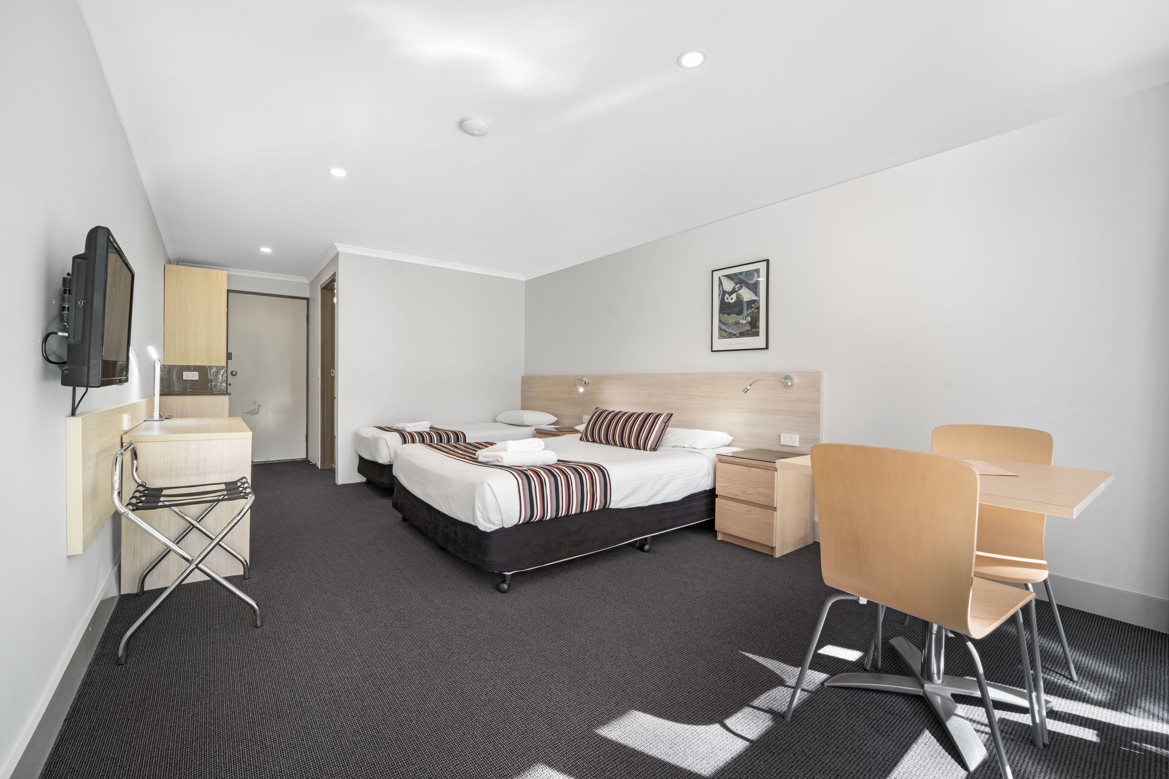 A modern hotel room with a large bed, bedside tables, a desk, and a chair.