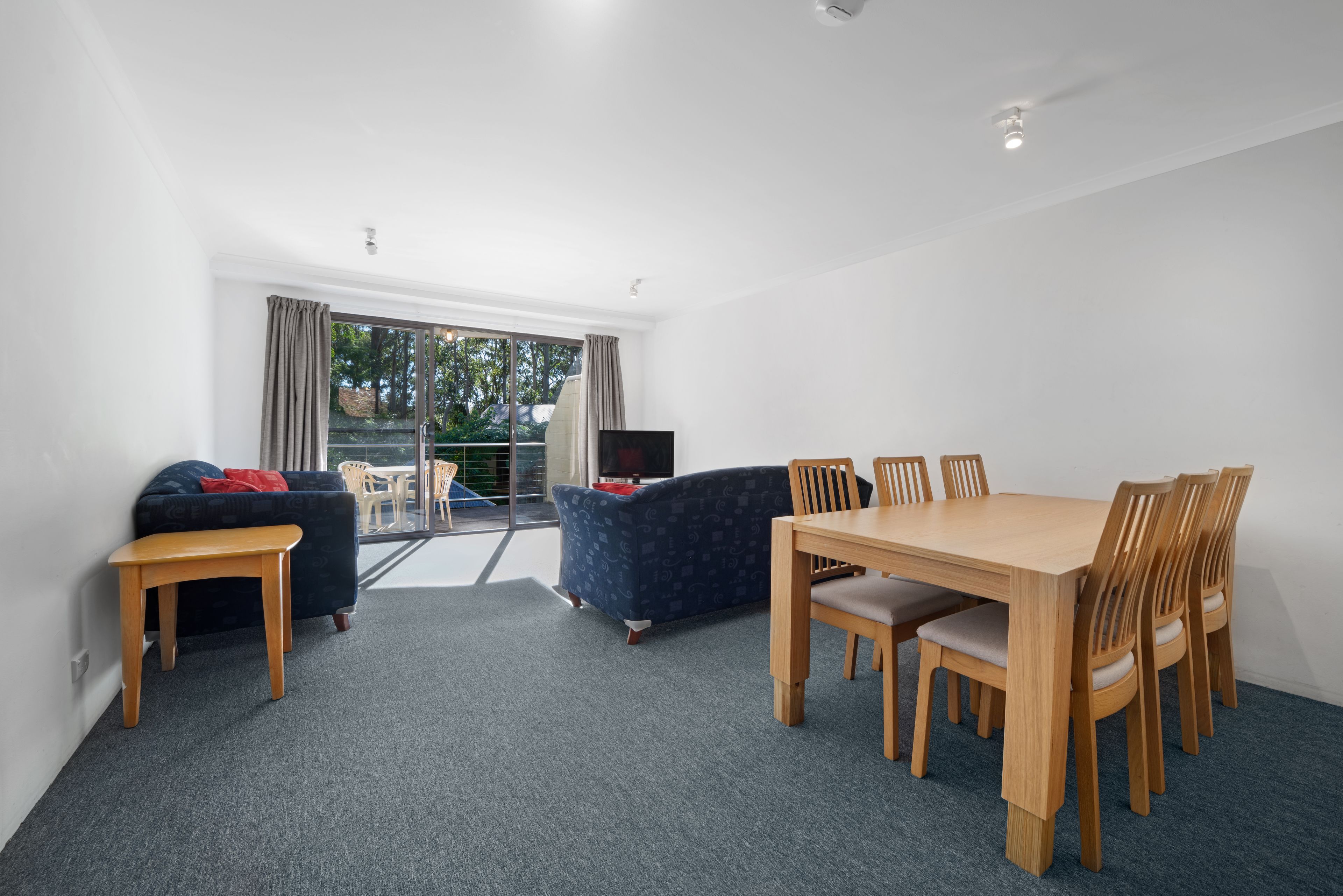 A modern living room with a dining area, a sofa, a small table, and a TV.