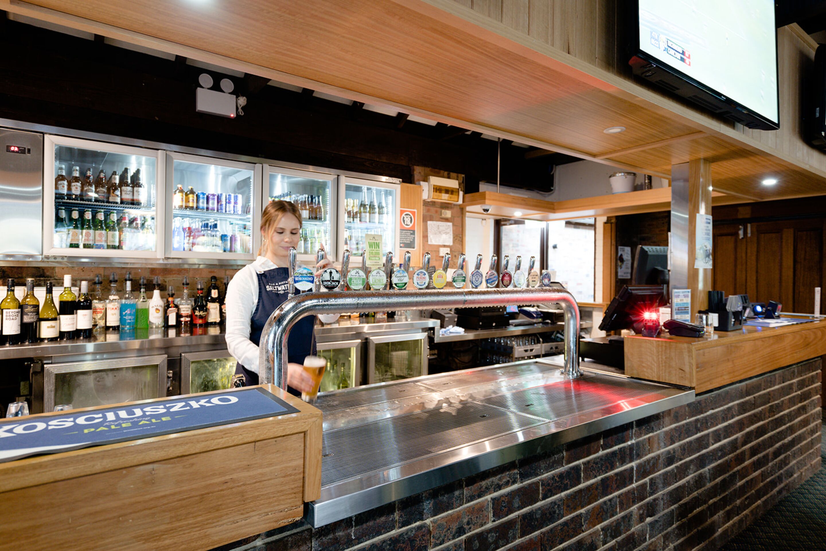 Eine Bar mit Bartender, Zapfhahn und einer Auswahl an Flaschen.