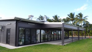 Un edificio moderno con un patio cubierto, amplios ventanales y techo plano.
