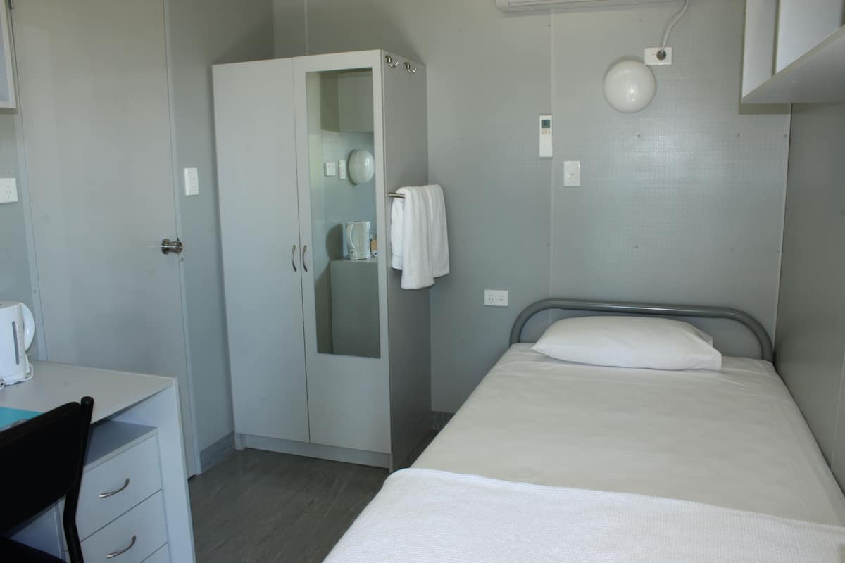 A small, clean room with a bed, a desk, and a wardrobe.
