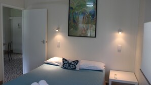 Un dormitorio con una cama, un almohadón con diseño de mariposa, una mesita de noche y un cuadro colgado en la pared.