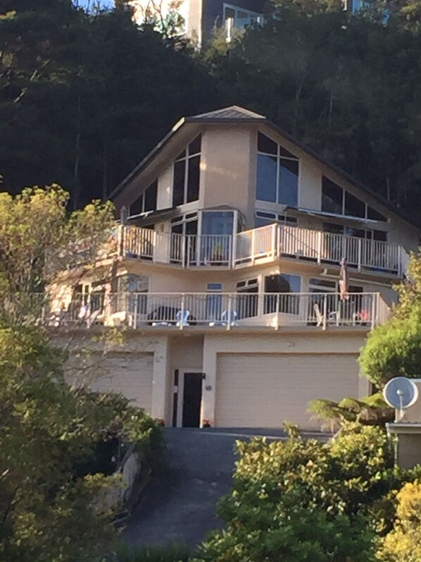 A multi-story building with balconies, a garage, and surrounded by greenery. - Absolute Bliss (Paihia)