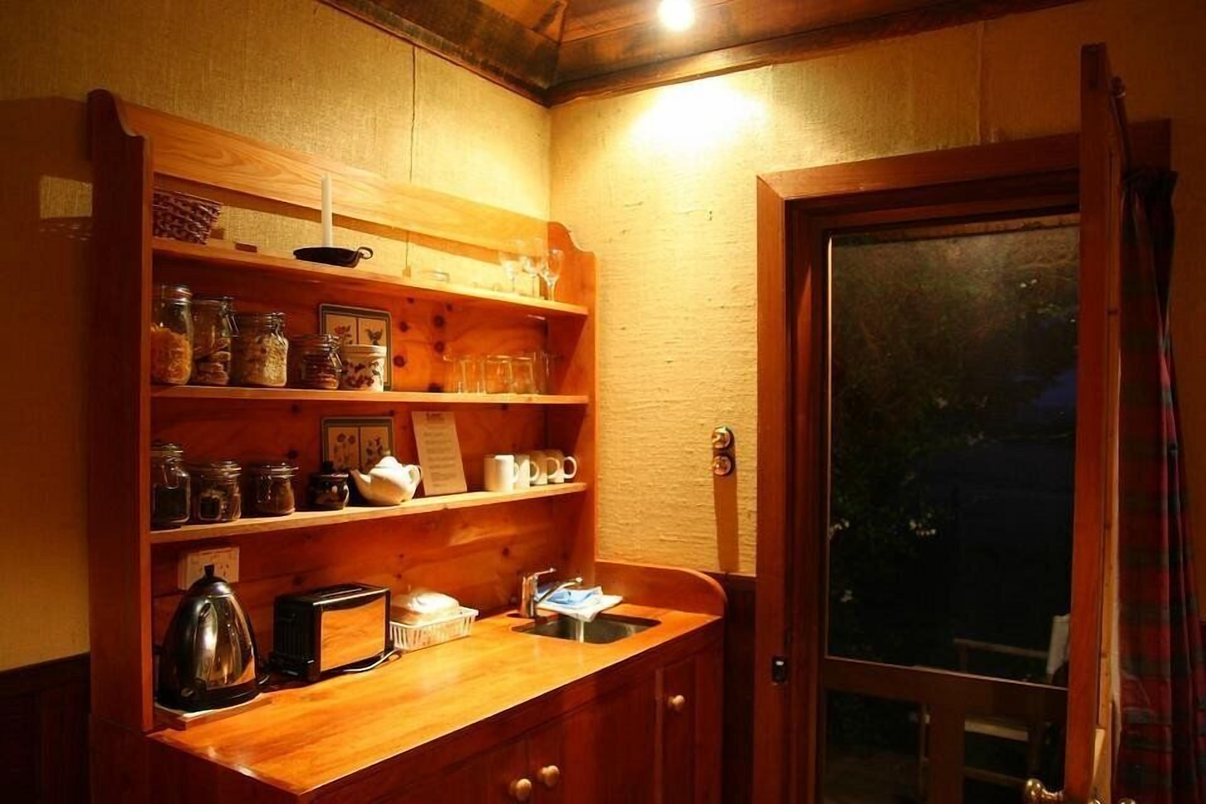Une cuisine compacte avec des étagères en bois, une bouilloire, un grille-pain et un évier.