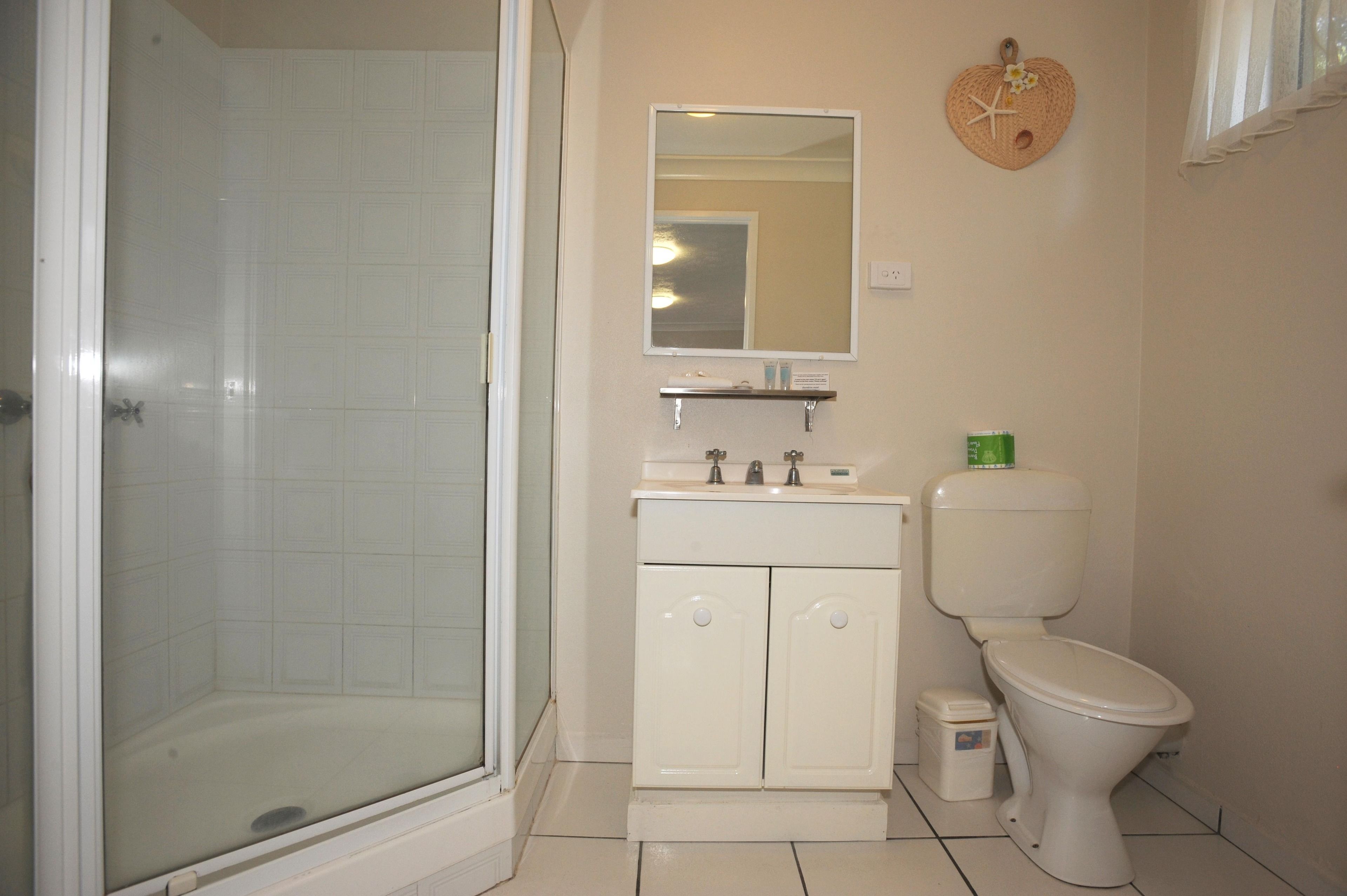 A bathroom with a shower, a sink with a mirror, and a toilet.