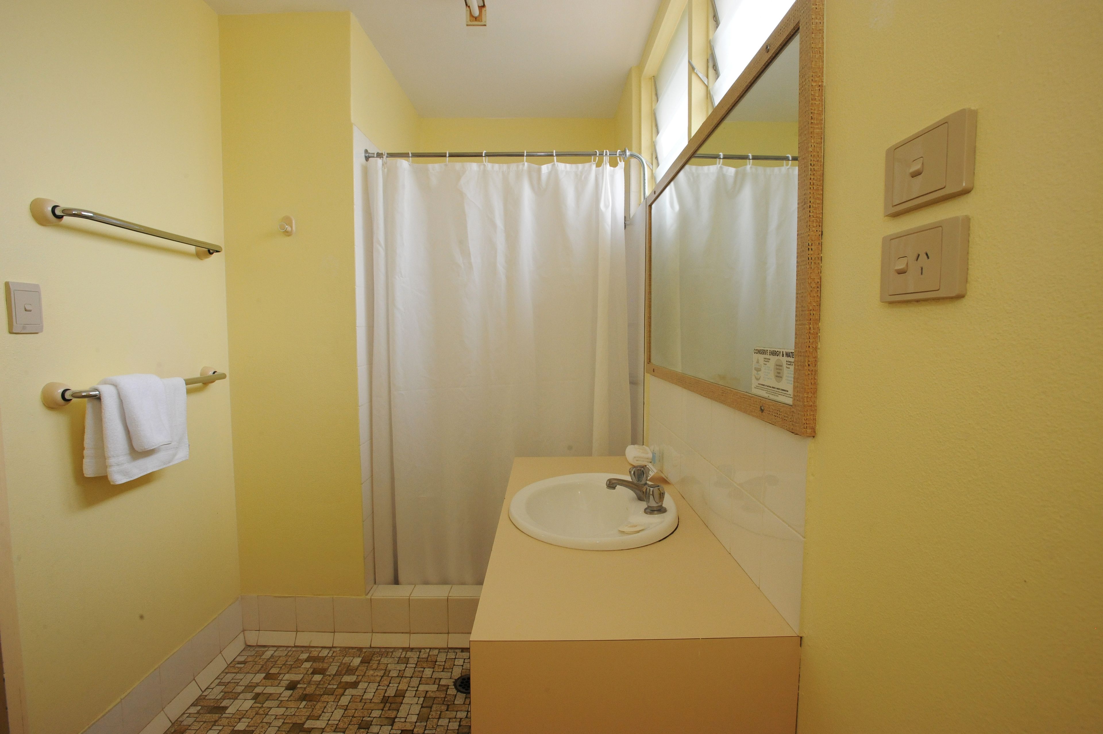 A bathroom with a white sink, a towel rack with a towel, a shower curtain, and a mirror.