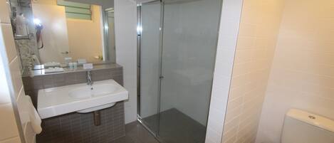 A modern bathroom with a glass-enclosed shower, a white sink, and a toilet.