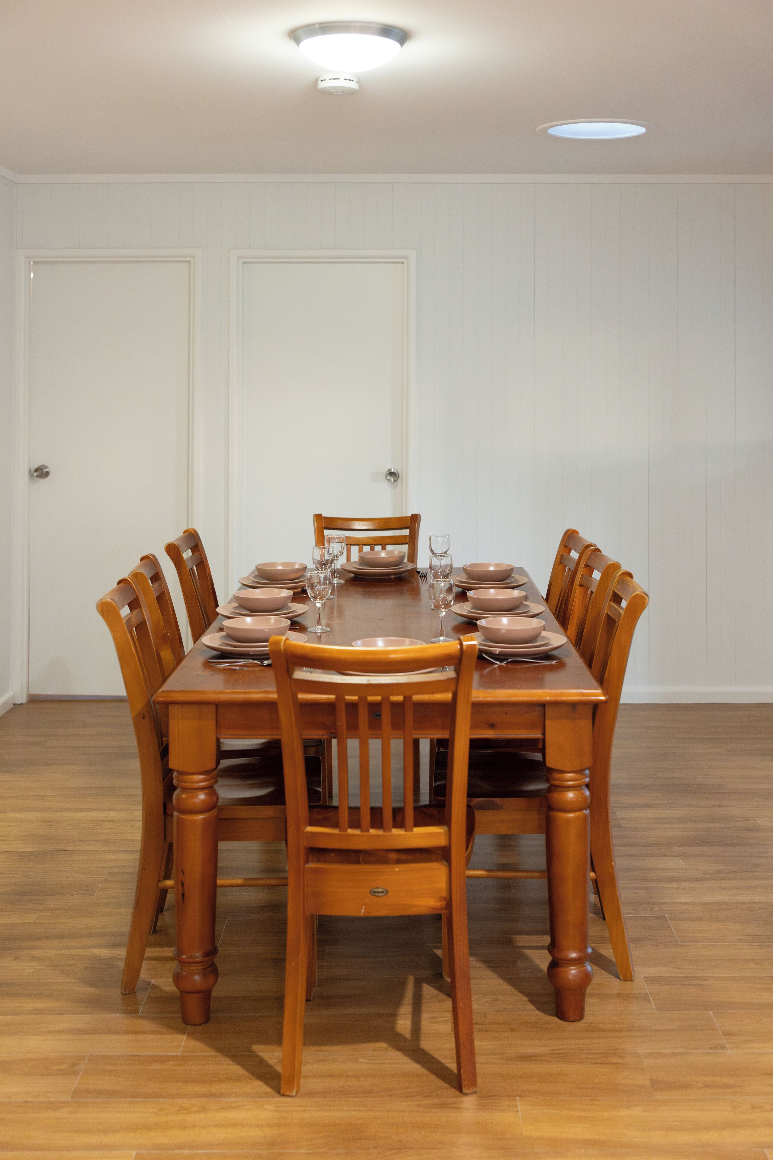 Comedor con una mesa de madera dispuesta para seis personas, rodeada por seis sillas de madera.