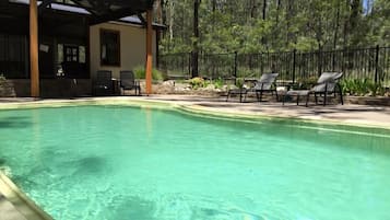 Relax by the tranquil pool surrounded by a shaded pergola and lounge chairs.
