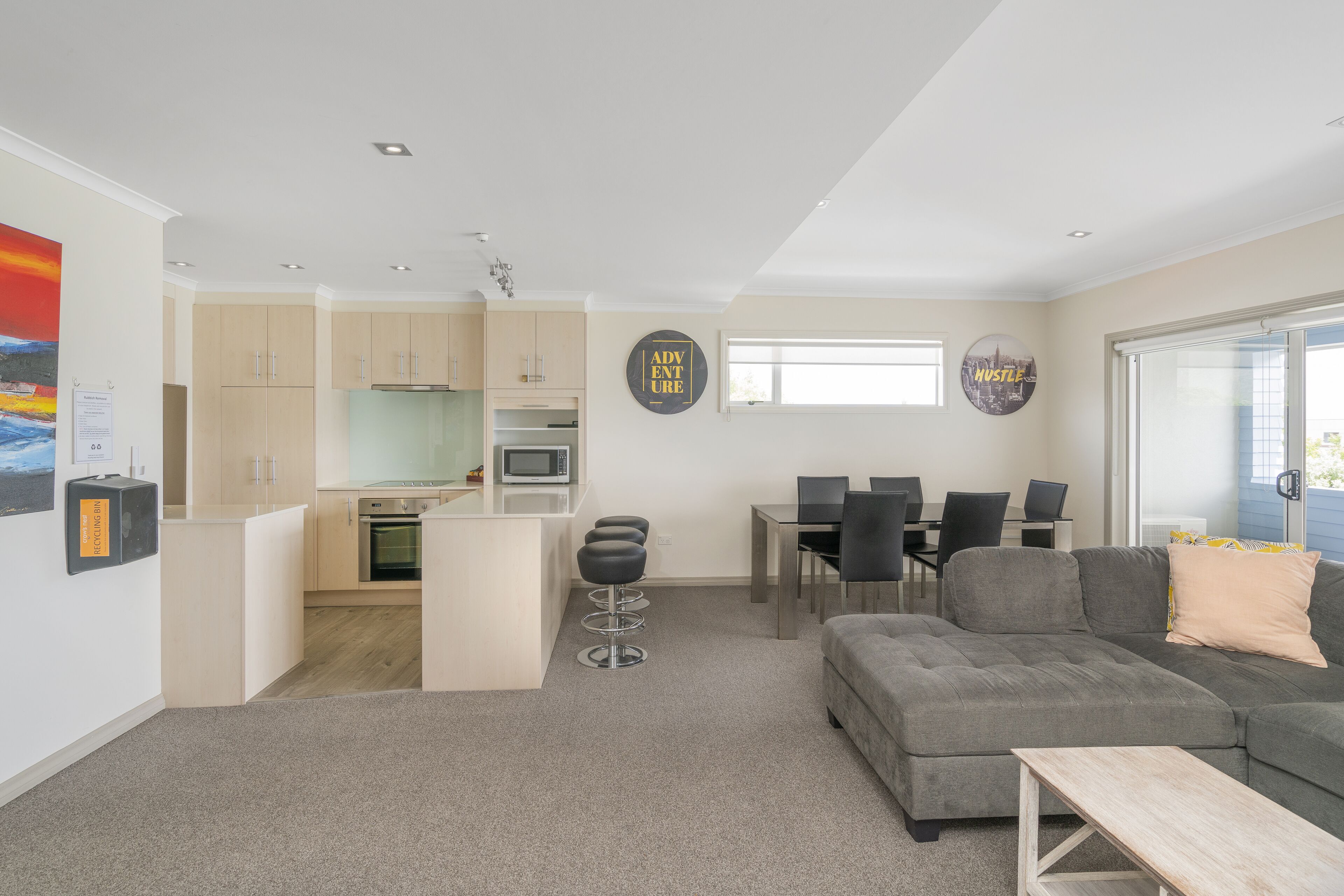 A modern living space with a kitchen, dining area, and a gray sectional sofa.