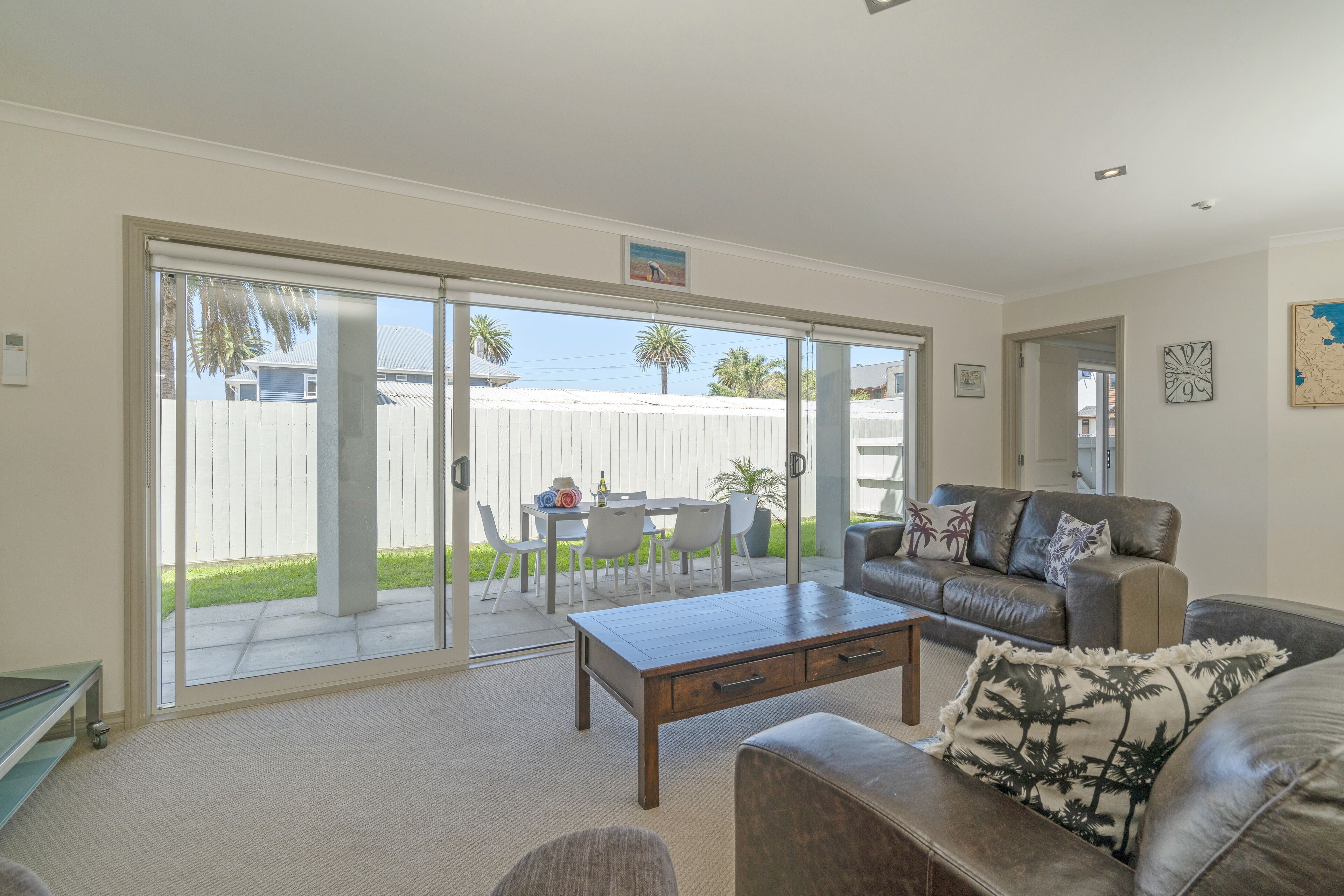 A living room with a sofa, a coffee table, and a dining area with chairs and a table.
