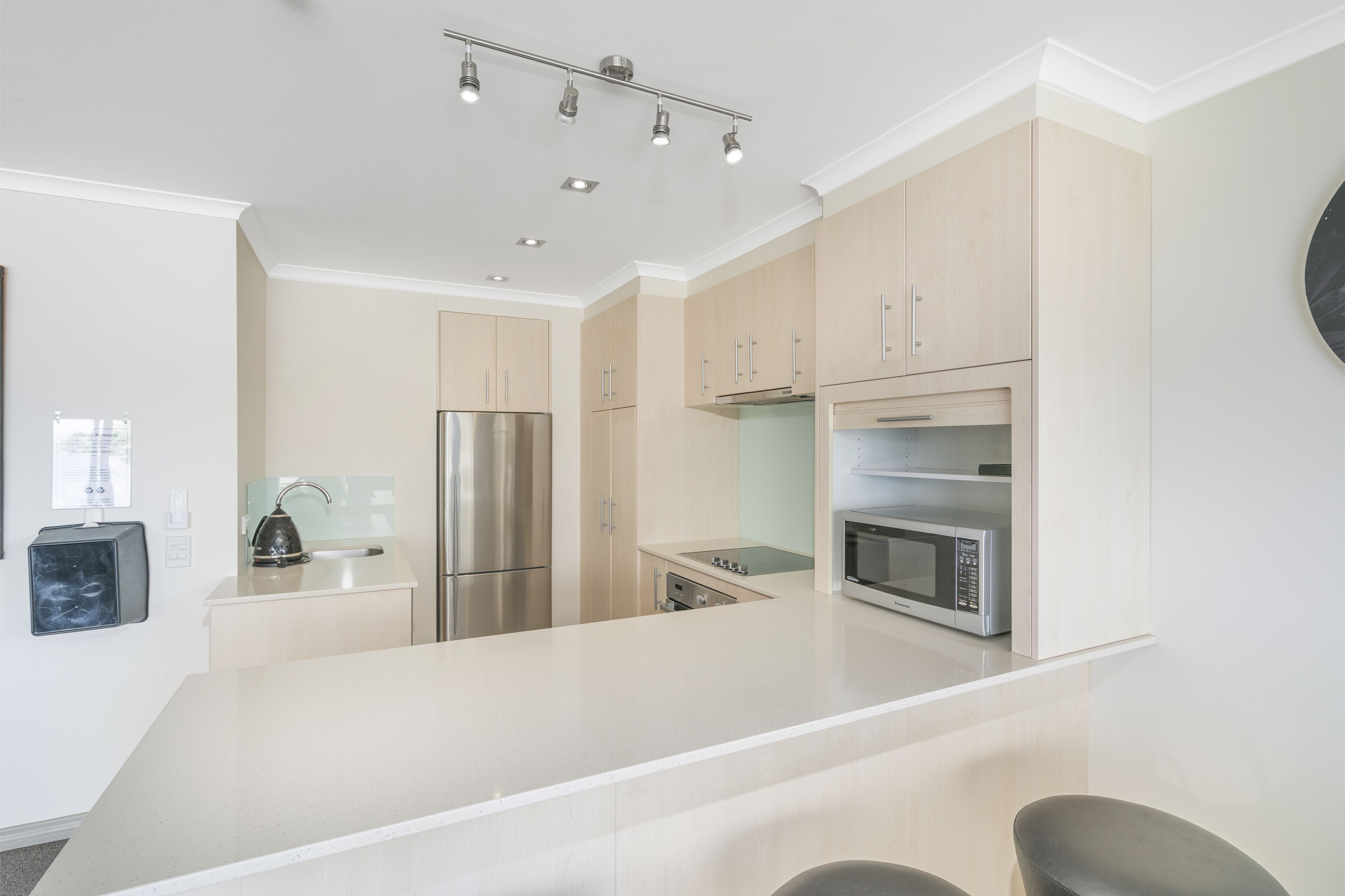 Una cocina moderna con electrodomésticos de acero inoxidable, armarios de tonos claros e una isla central.