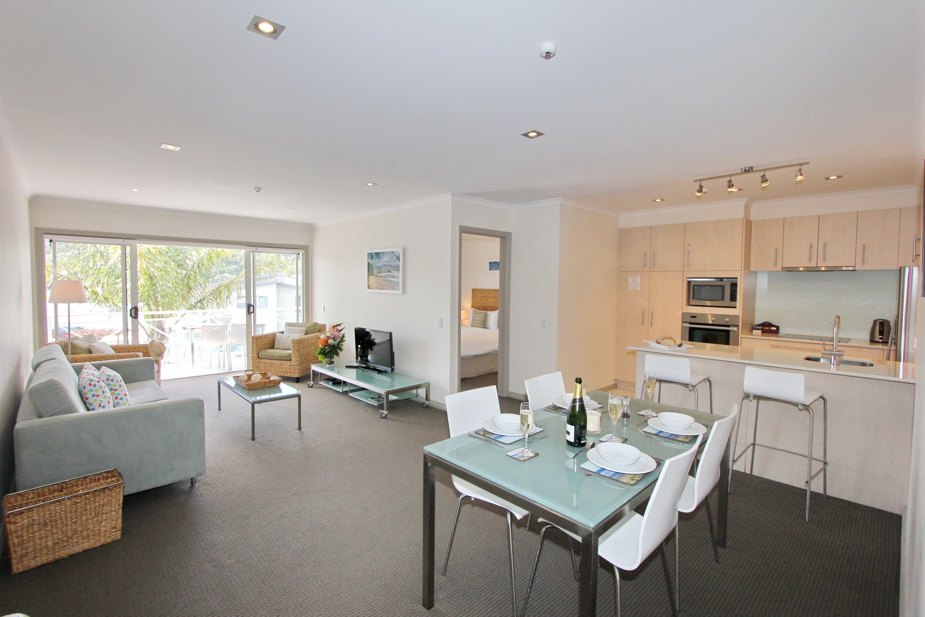 A modern living room with a sofa, TV, and dining area with chairs and a table set for a meal.