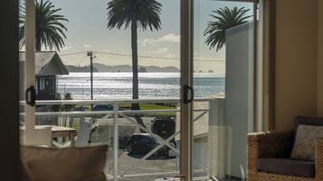 Un balcon avec vue sur la mer, les palmiers et les voitures garées.