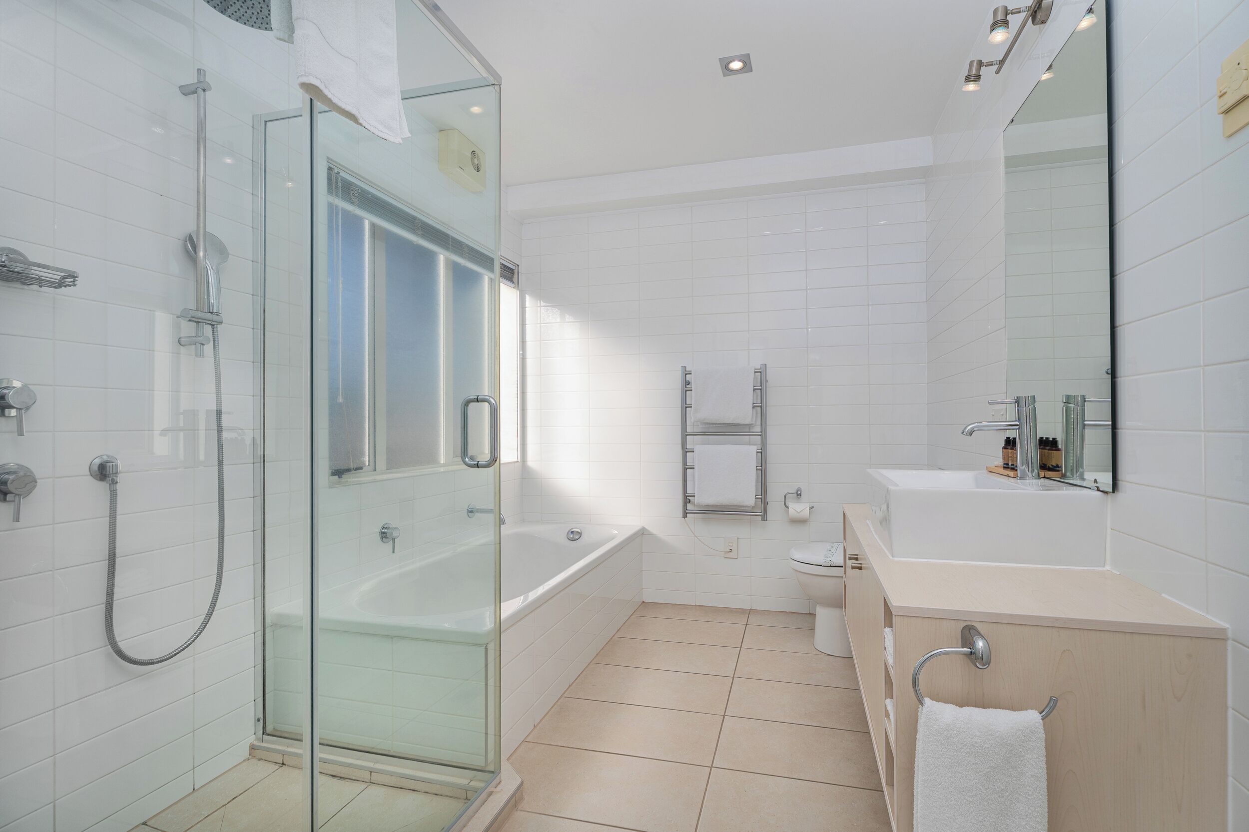 Een moderne badkamer met een douchecabine van glas, een vrijstaand bad, een wastafel met spiegel en een toilet.