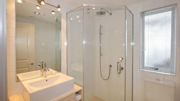 A modern bathroom with a glass-enclosed shower, a white sink, and a large mirror.