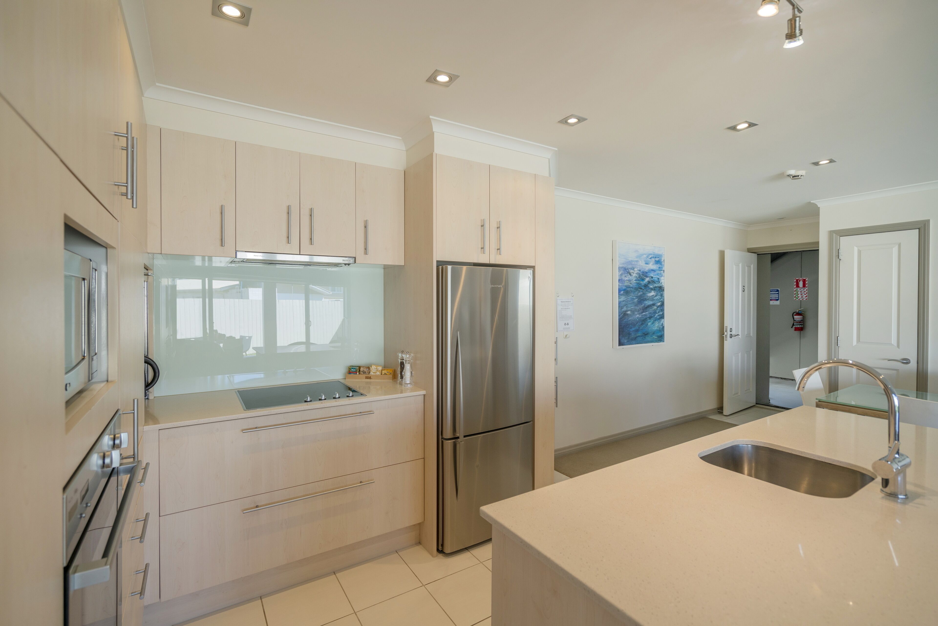 A modern kitchen with light-colored cabinets, stainless steel appliances, and a large island with a sink.