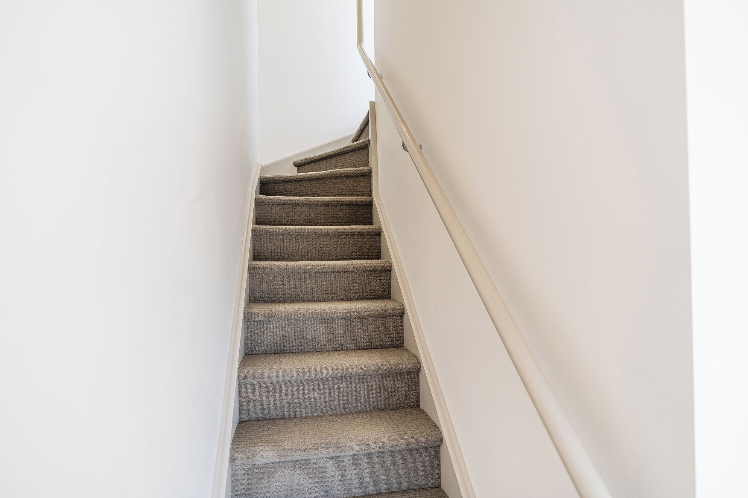 Una escalera alfombrada con barandilla que conduce a un piso superior.