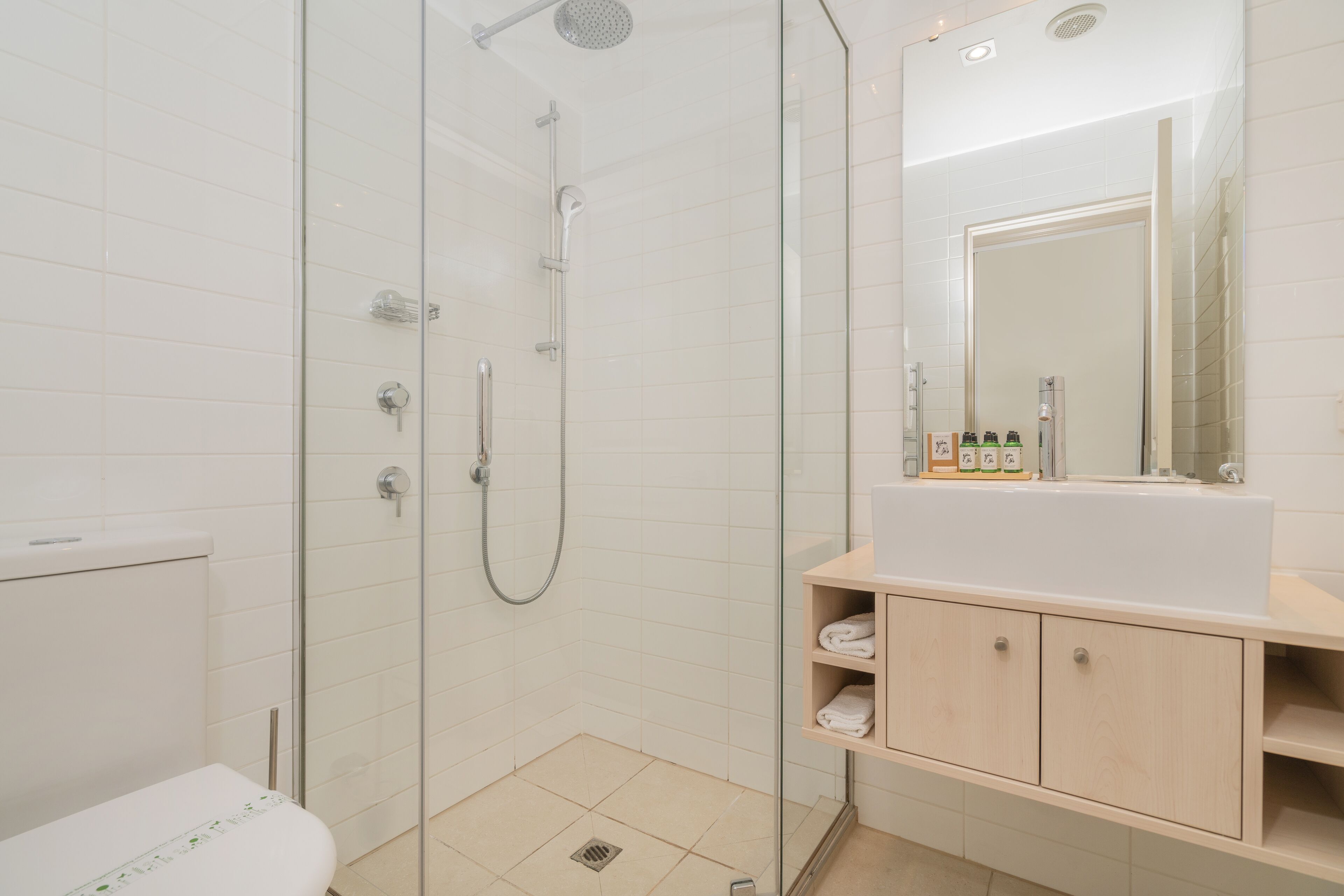 A modern bathroom with a glass-enclosed shower, a white sink, and a mirror above the sink.