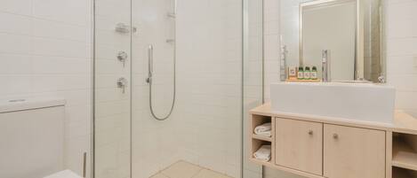 A modern bathroom with a glass-enclosed shower, a white sink, and a mirror above the sink.