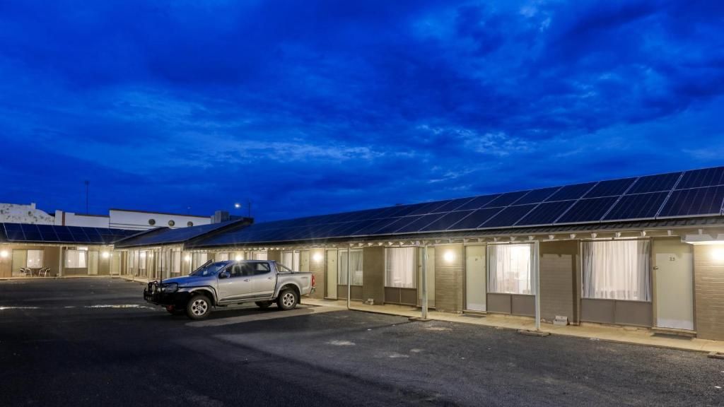 Un hôtel avec une série de chambres, un parking et un camion garé à l’extérieur.