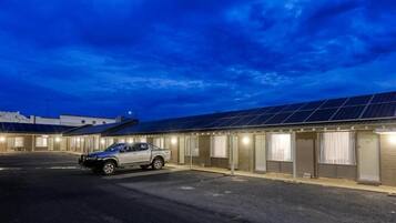 Un hotel con una hilera de habitaciones, un estacionamiento y un camión estacionado afuera.