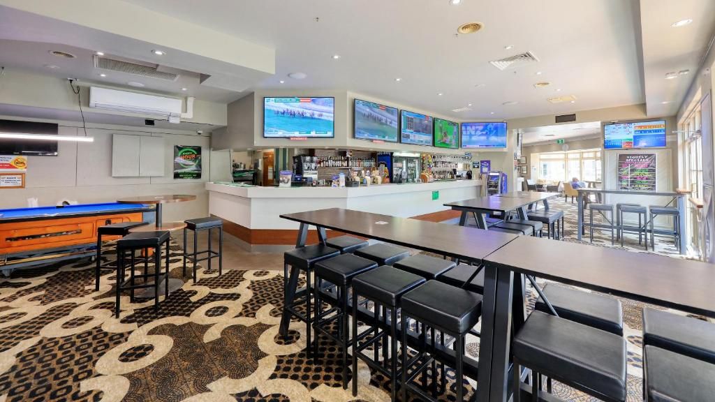 Zona de bar con mesa de billar, diversas opciones de asientos y una barra con exhibición de bebidas.