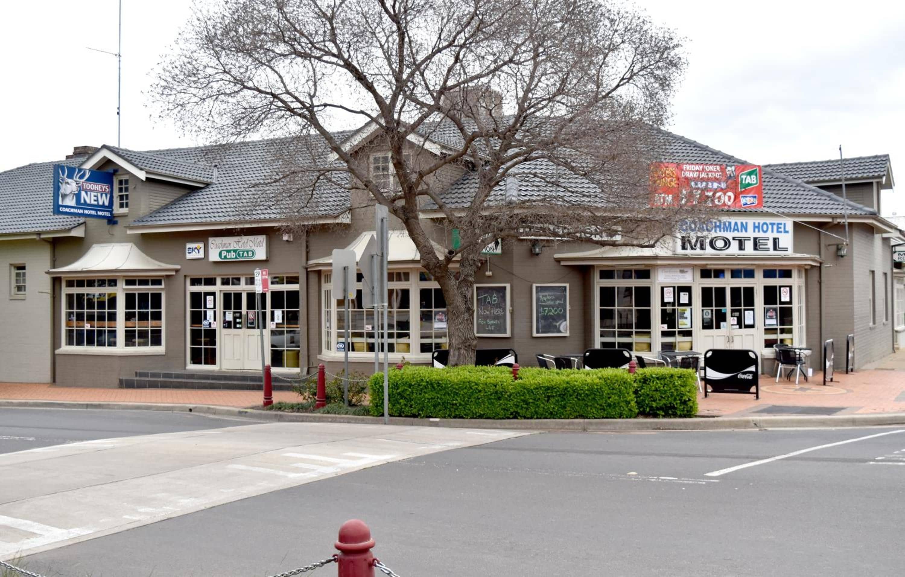 A Coachman Hotel Motel with a Pub sign, outdoor seating, and a fire hydrant.
