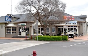 A Coachman Hotel Motel with a Pub sign, outdoor seating, and a fire hydrant. - Coachman Hotel Motel (Parkes)