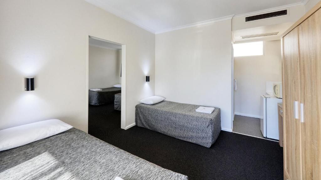Una habitación de hotel con una cama, un escritorio pequeño, un armario y una puerta que da a un baño.