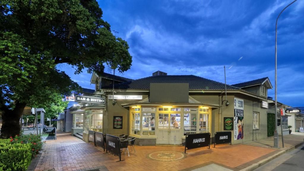 A bar and restaurant with a brick facade, outdoor seating, and a signboard advertising 'Hair by Harlow.'