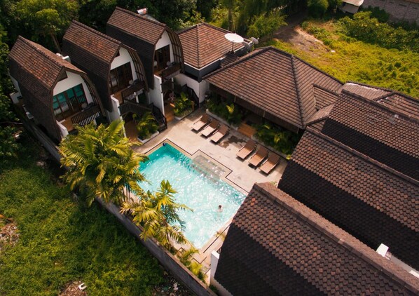 A resort with multiple villas, a swimming pool, and lush greenery.