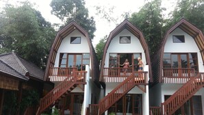 A two-story building with a balcony on each floor, wooden stairs, and a pool area with lounge chairs. - Mojo Resort (Canggu)