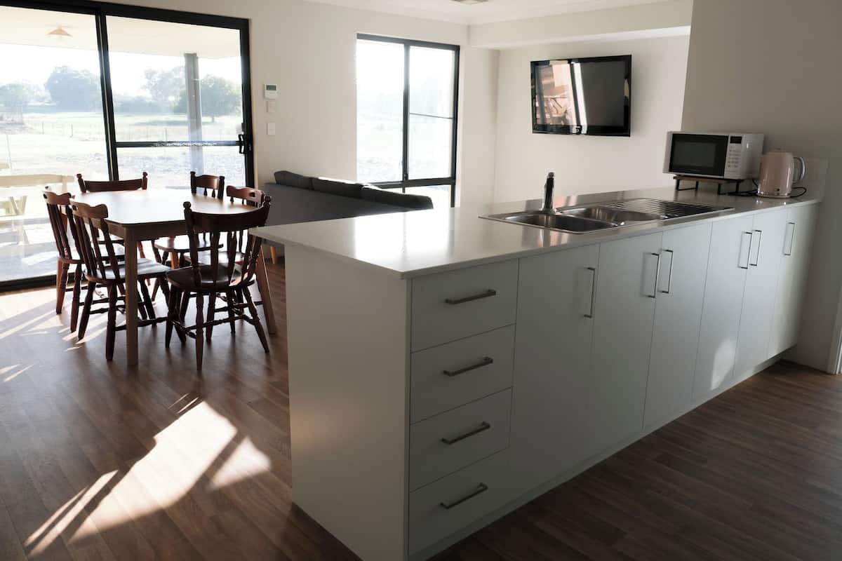 A modern kitchen with a large island, white cabinetry, and a dining area with wooden chairs.