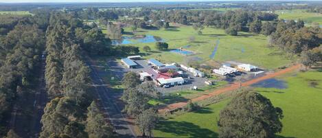 An aerial view of a rural property with multiple buildings, a parking area, and surrounding greenery.