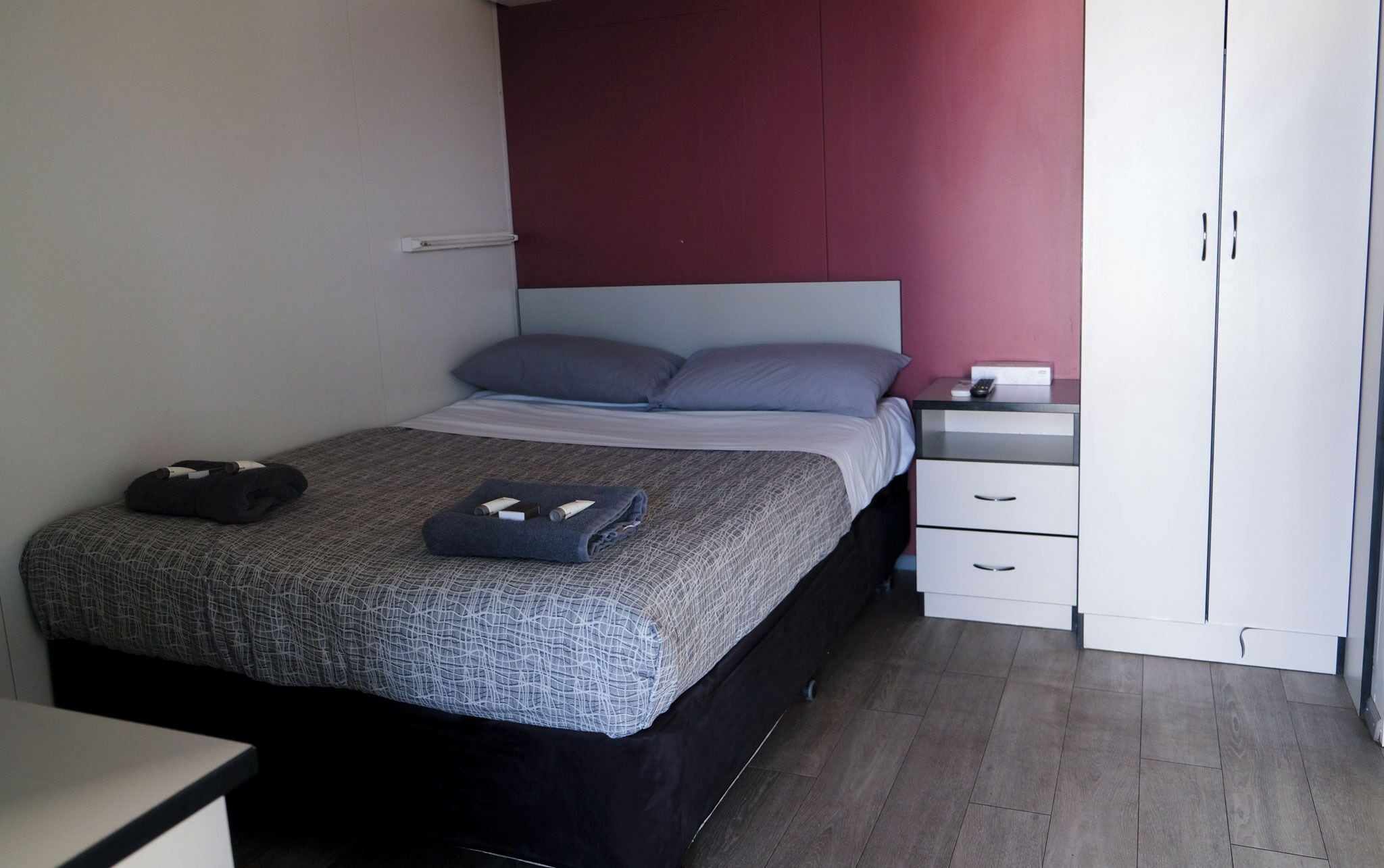A neatly arranged bedroom with a bed, bedside tables, and a wardrobe.