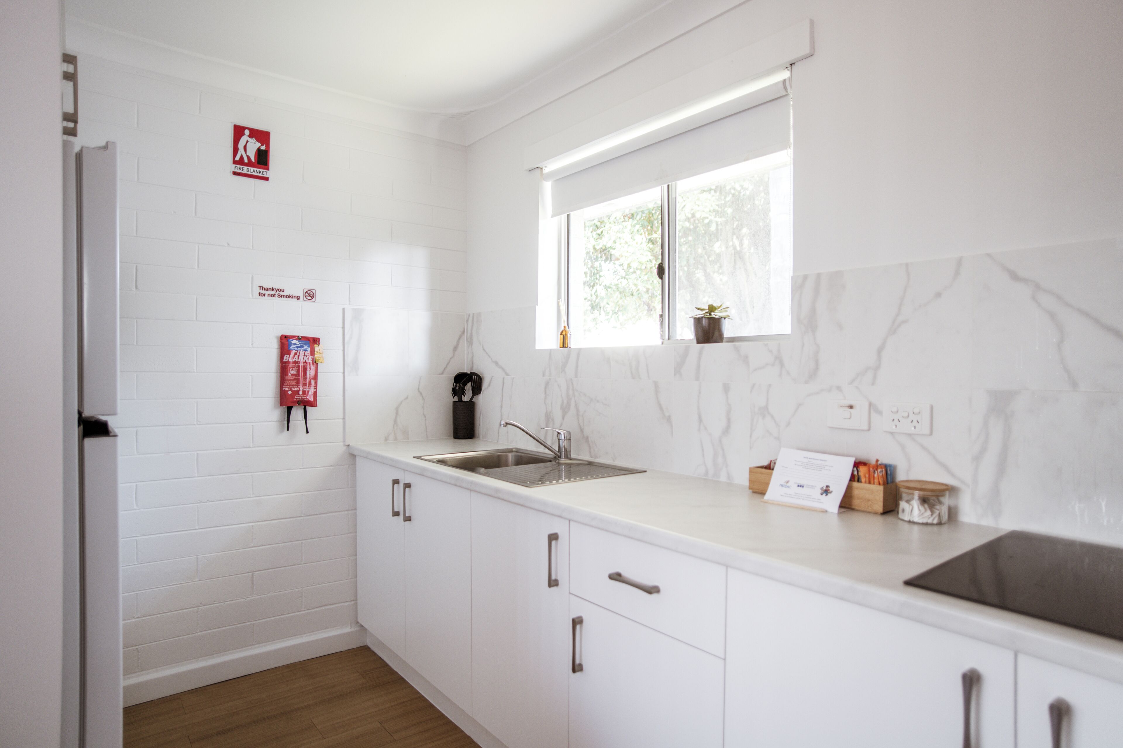 A modern kitchen with white cabinetry, a stainless steel sink, and a window above the countertop.